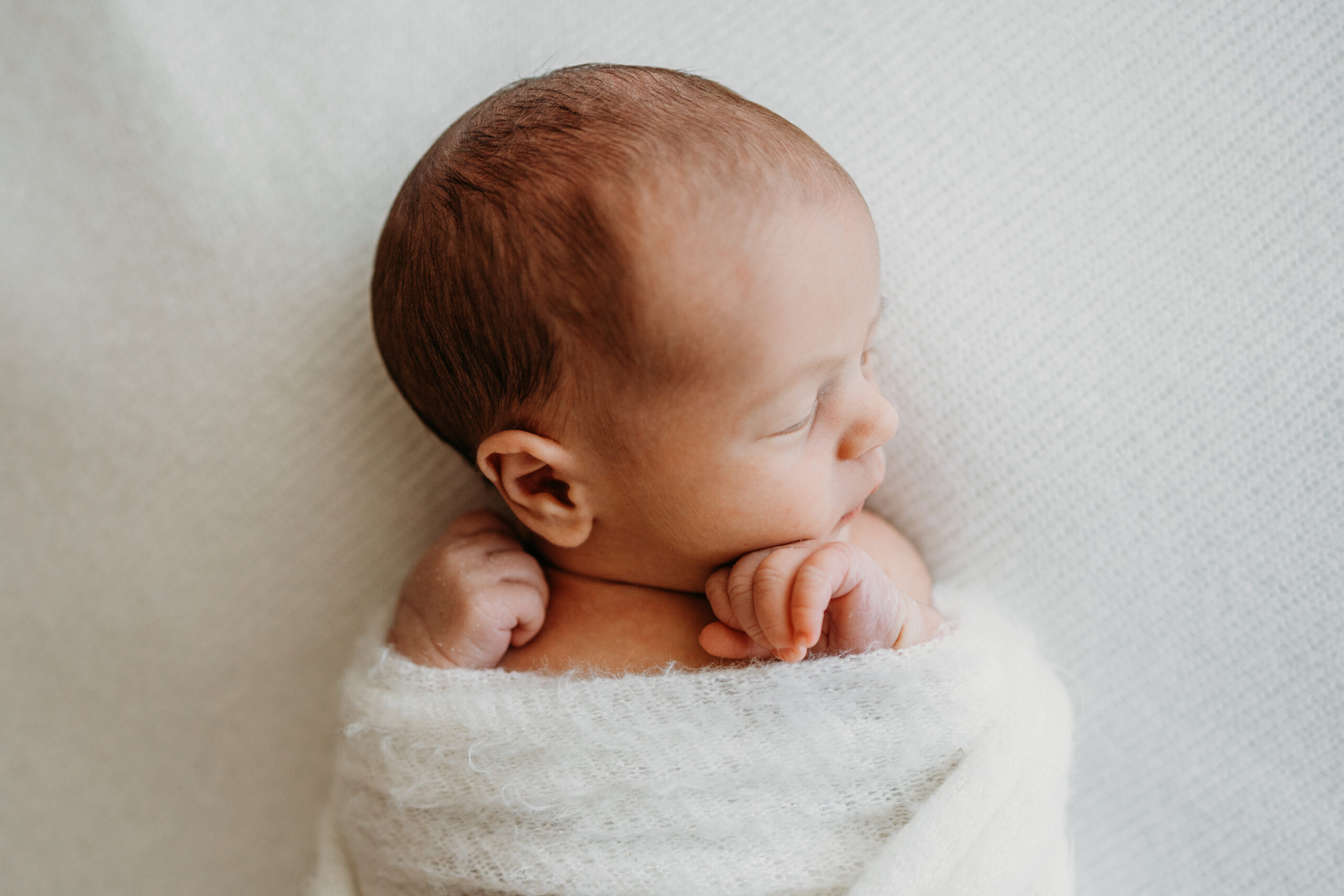 Neugeborenes auf einer weissendecke beim Natürlichem Newborn Fotoshooting im Zürich Oberland
